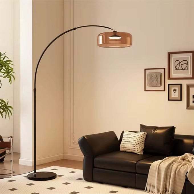 Arching copper-shade floor lamp over a black leather sofa on a black-and-white patterned rug.