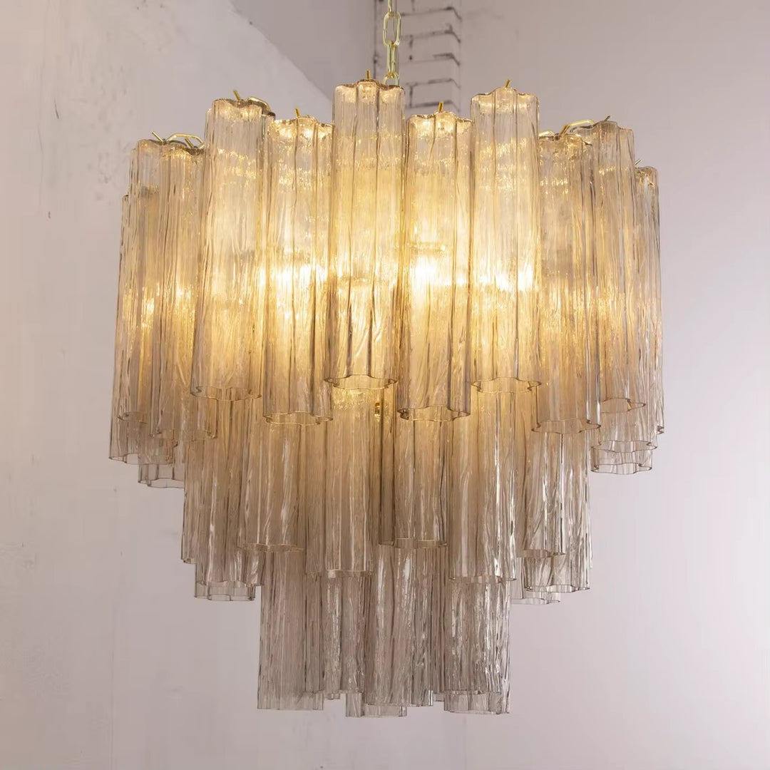 Gold-tone chandelier with cascading textured glass tubes and warm glowing light