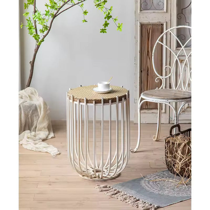 Wicker side table with a white chair and decorative elements in a room setting.