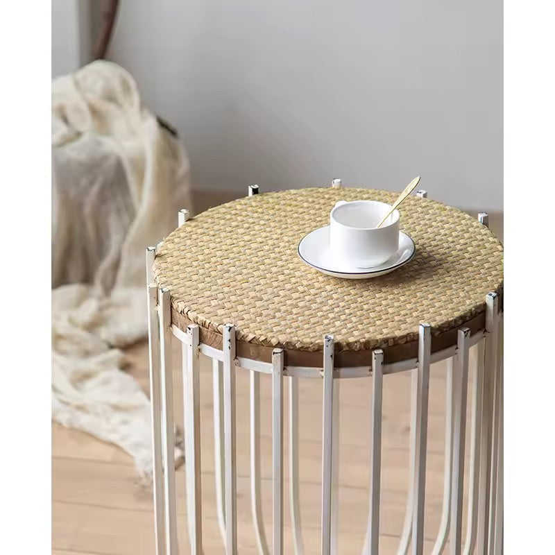 Round woven table with a white cup and saucer on a light wooden floor.