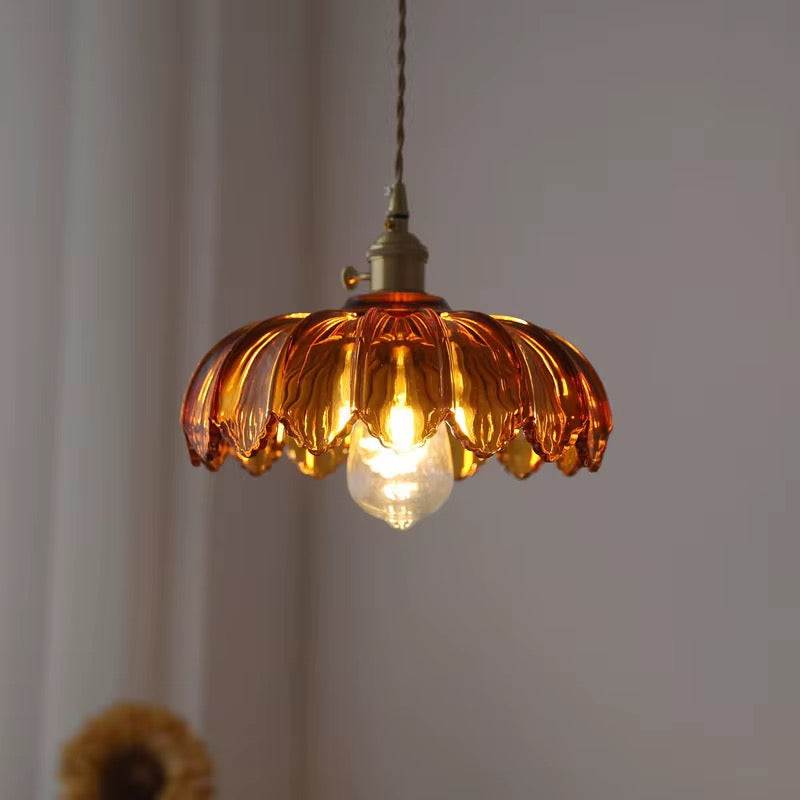 Amber vintage glass pendant with scalloped design and brass fixture emitting warm glow