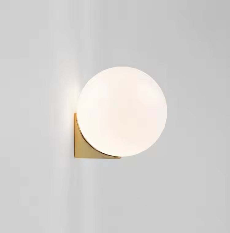 Modern brass wall light with frosted glass globe for contemporary interiors