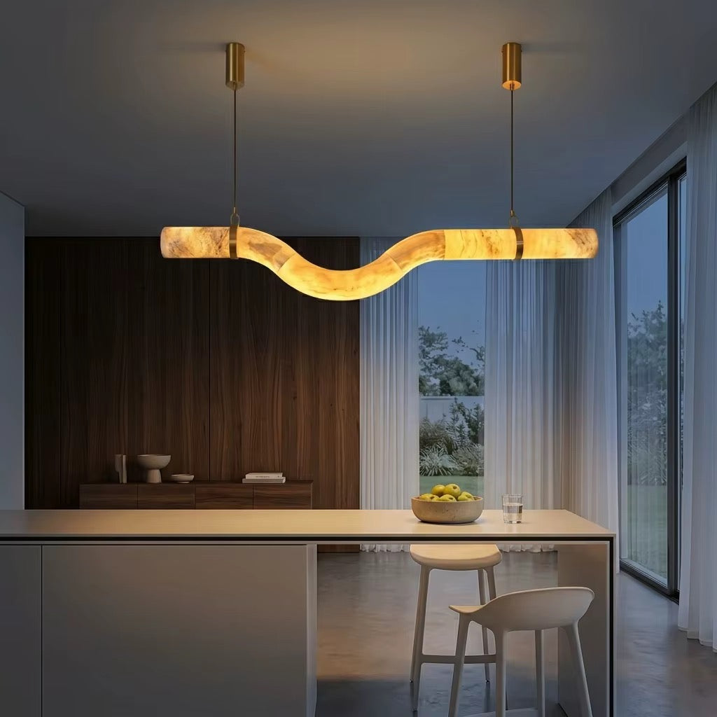 Modern wave-shaped marble-effect LED pendant light with brass suspension hanging above a contemporary kitchen island.