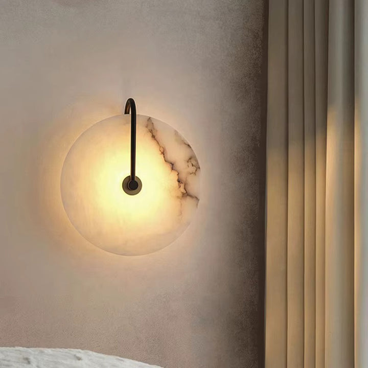 Round marble wall sconce with warm glow and slim black arm