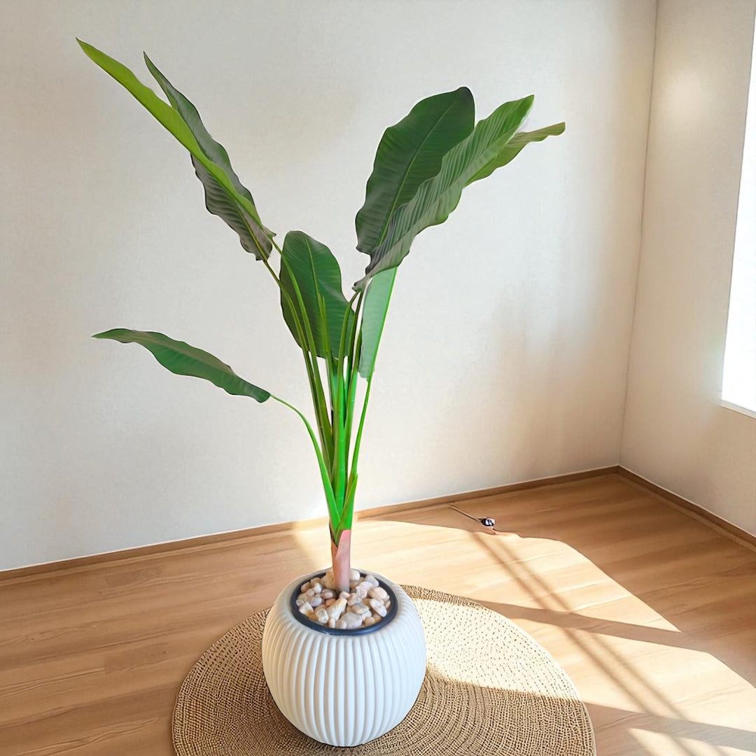 Tall artificial banana leaf plant in textured white round pot for modern interiors