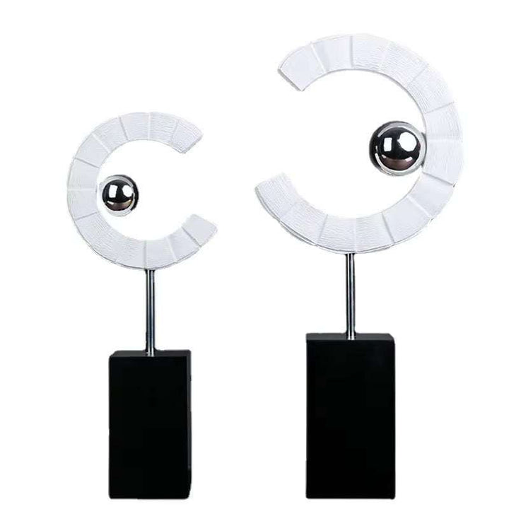 Set of 2 modern abstract sculptures with white crescent shapes and silver spheres on black bases