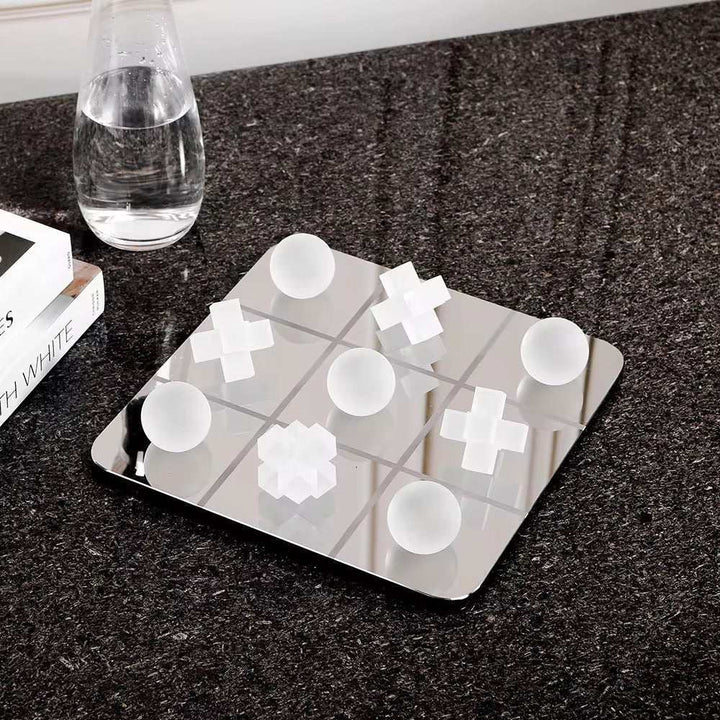Modern Tic Tac Toe glass board with sculpted playing pieces on a stylish surface