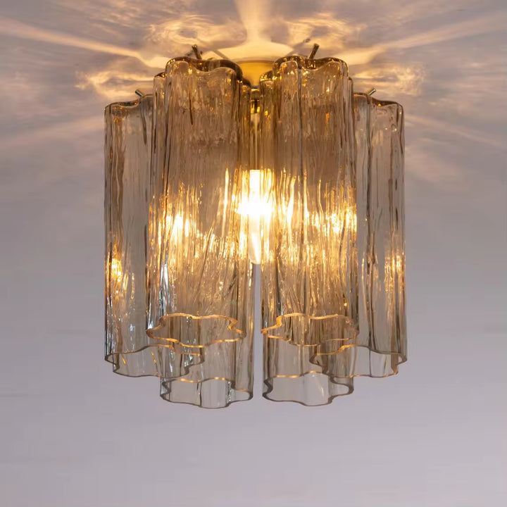 Clear textured glass chandelier with multiple wavy shades and warm golden illumination