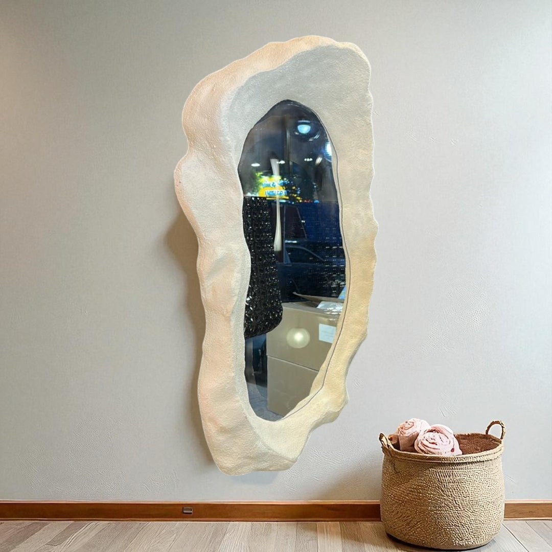 Irregular sculptural mirror with textured beige frame on neutral wall