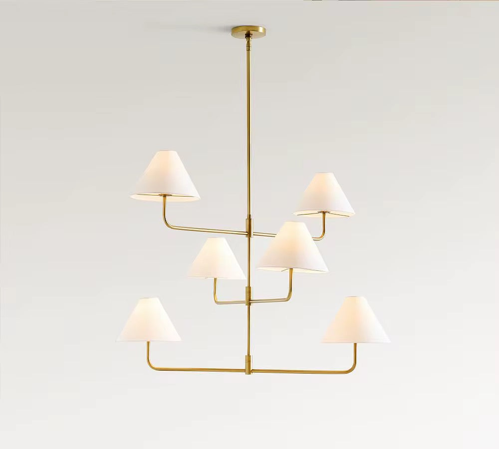 Modern brass multi-tier chandelier with six white fabric lampshades suspended from a ceiling mount