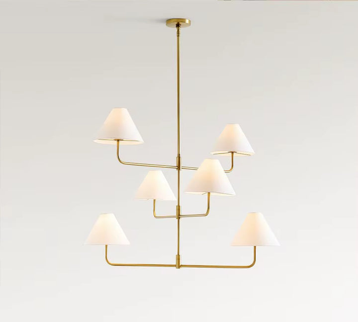 Modern brass multi-tier chandelier with six white fabric lampshades suspended from a ceiling mount