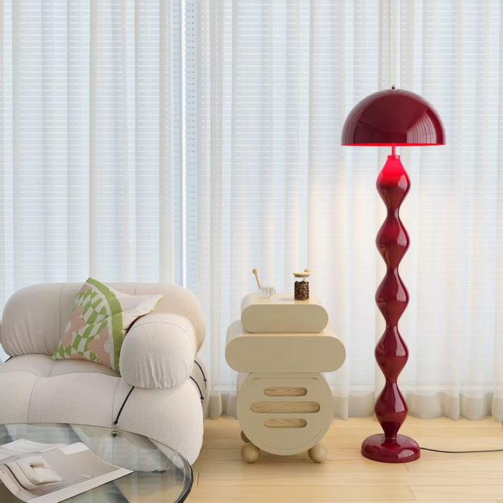 Sculptural burgundy red floor lamp with a twisted decorative base and dome shade in a modern living room
