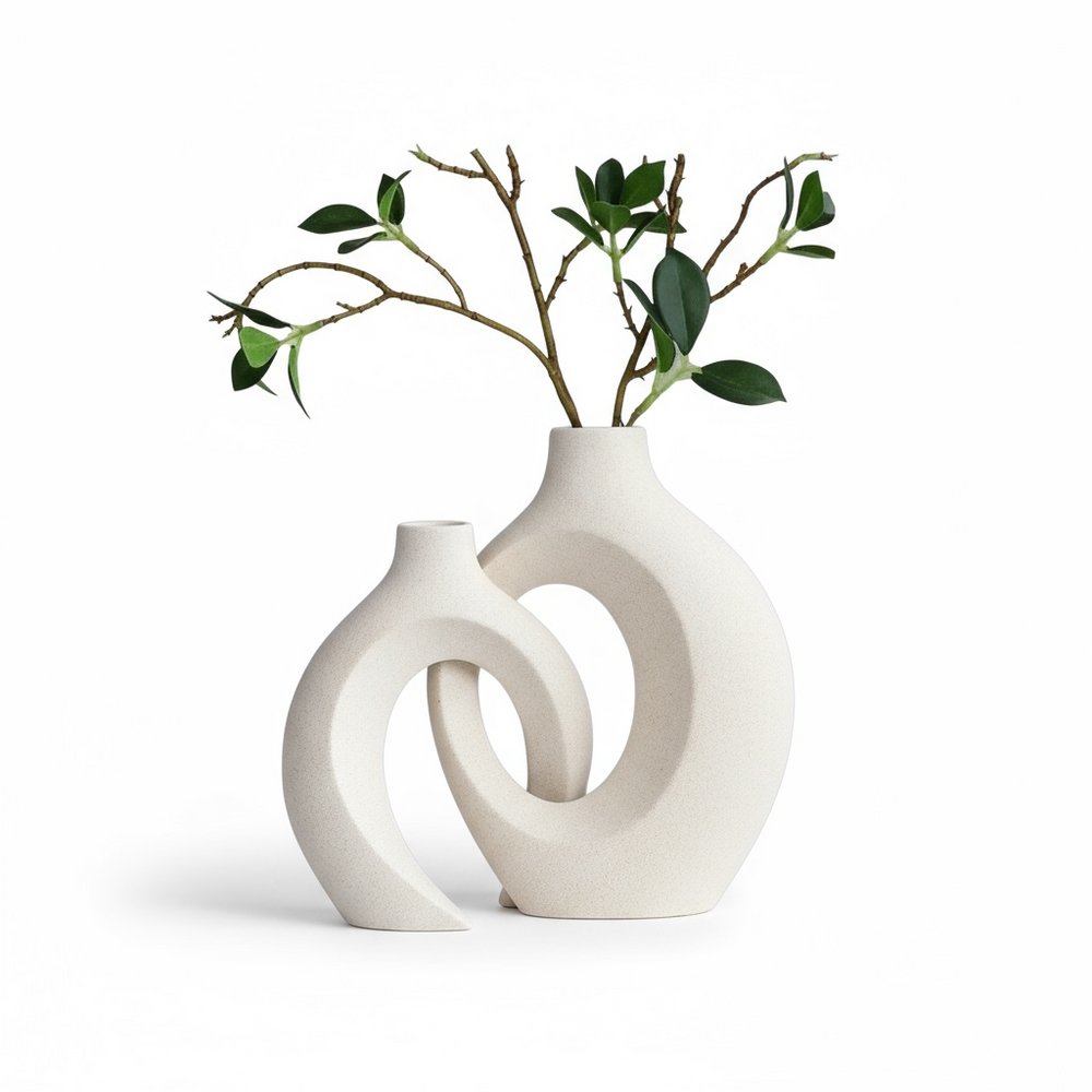White ceramic vase with circular design holding green branches on a white background