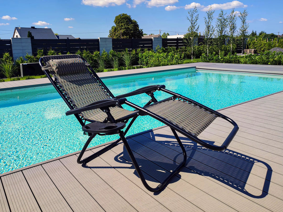 Black woven reclining lounge chair beside a swimming pool on a wooden deck