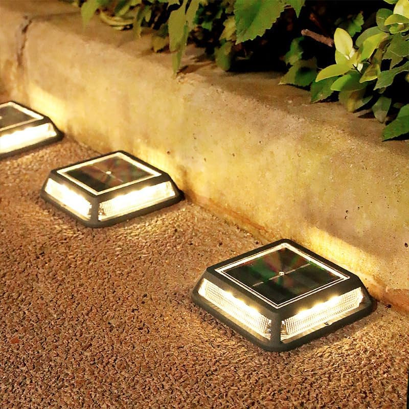 Low-profile black solar pathway lights glowing along a garden border