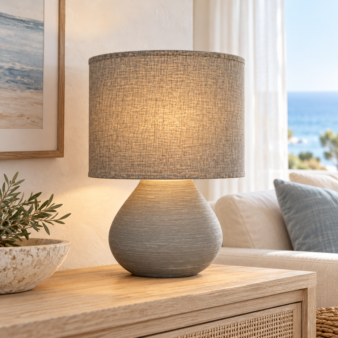Gray table lamp with a rounded textured base and matching drum shade