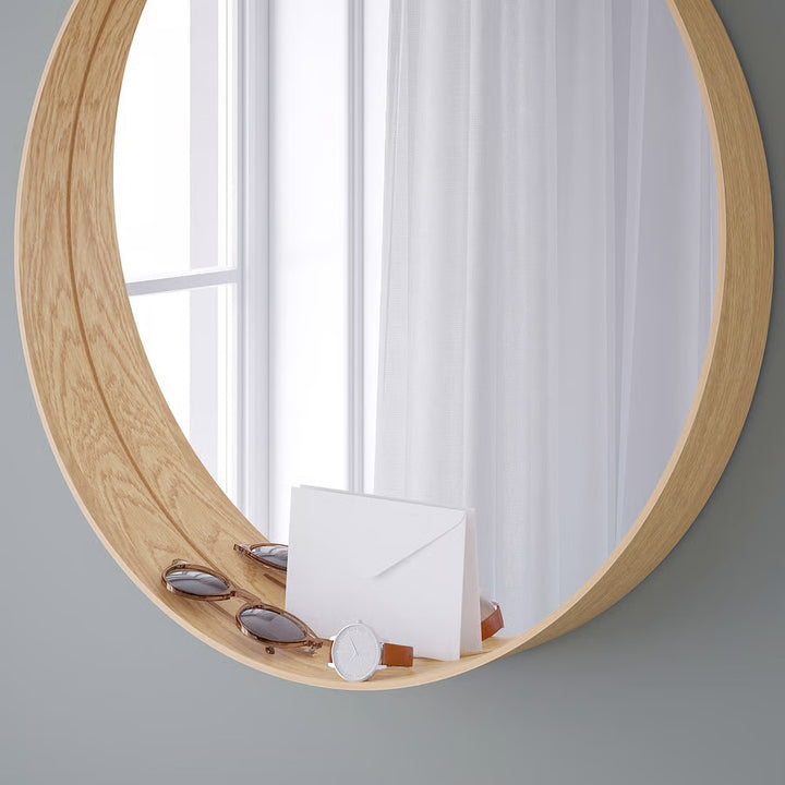 Round wooden mirror on a gray wall with white curtains in the reflection