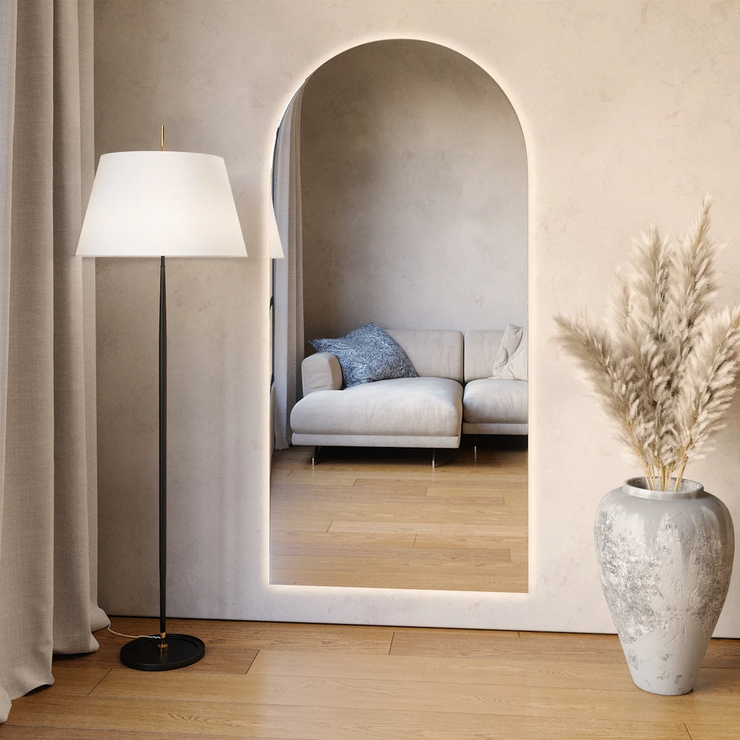 Arched LED wall mirror with warm backlighting in a modern living room interior