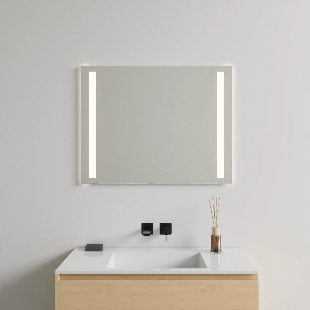 Frameless LED mirror with vertical side lights mounted above white vanity