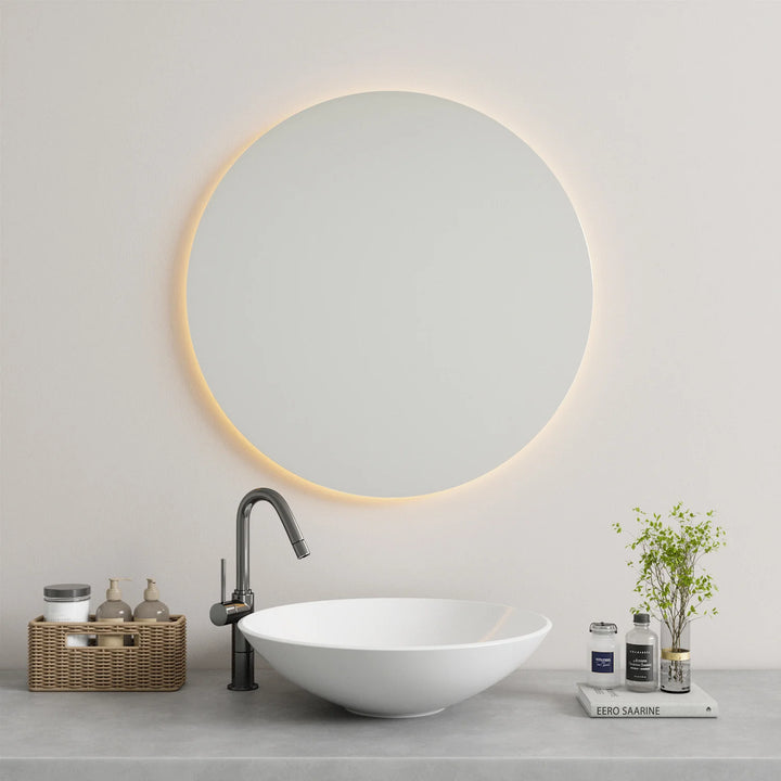Modern round LED backlit mirror mounted above a minimalist bathroom vanity with a vessel sink