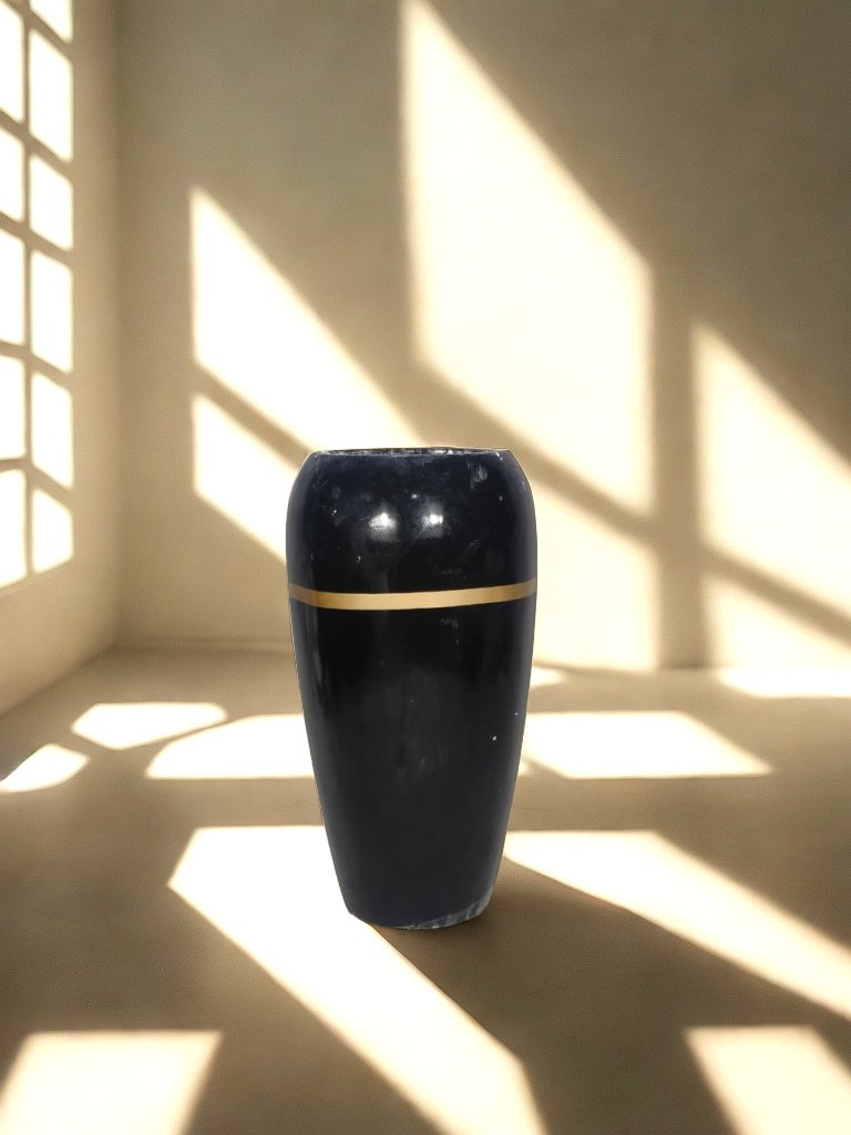Tall glossy black fiberglass planter with a narrow gold-tone band in a softly lit neutral interior.