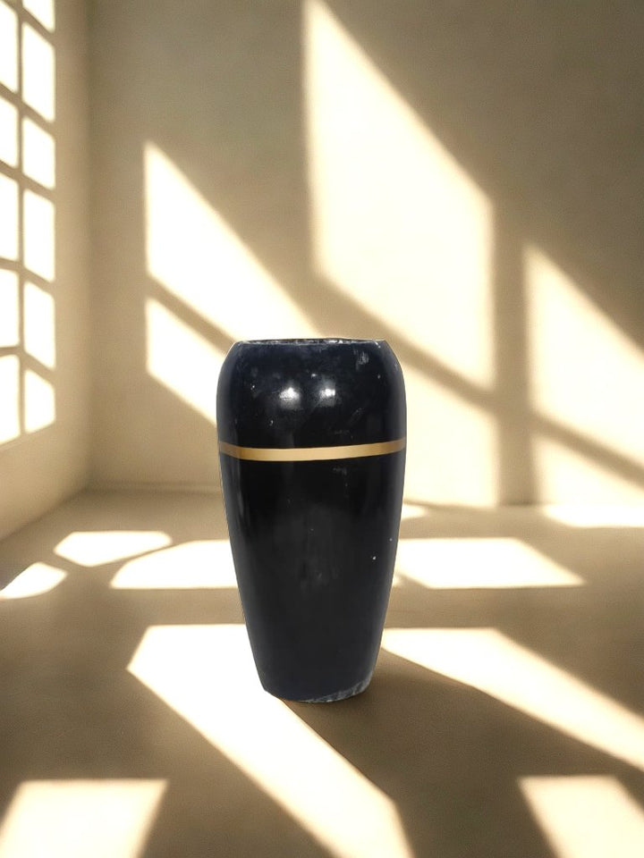 Tall glossy black fiberglass planter with a narrow gold-tone band in a softly lit neutral interior.