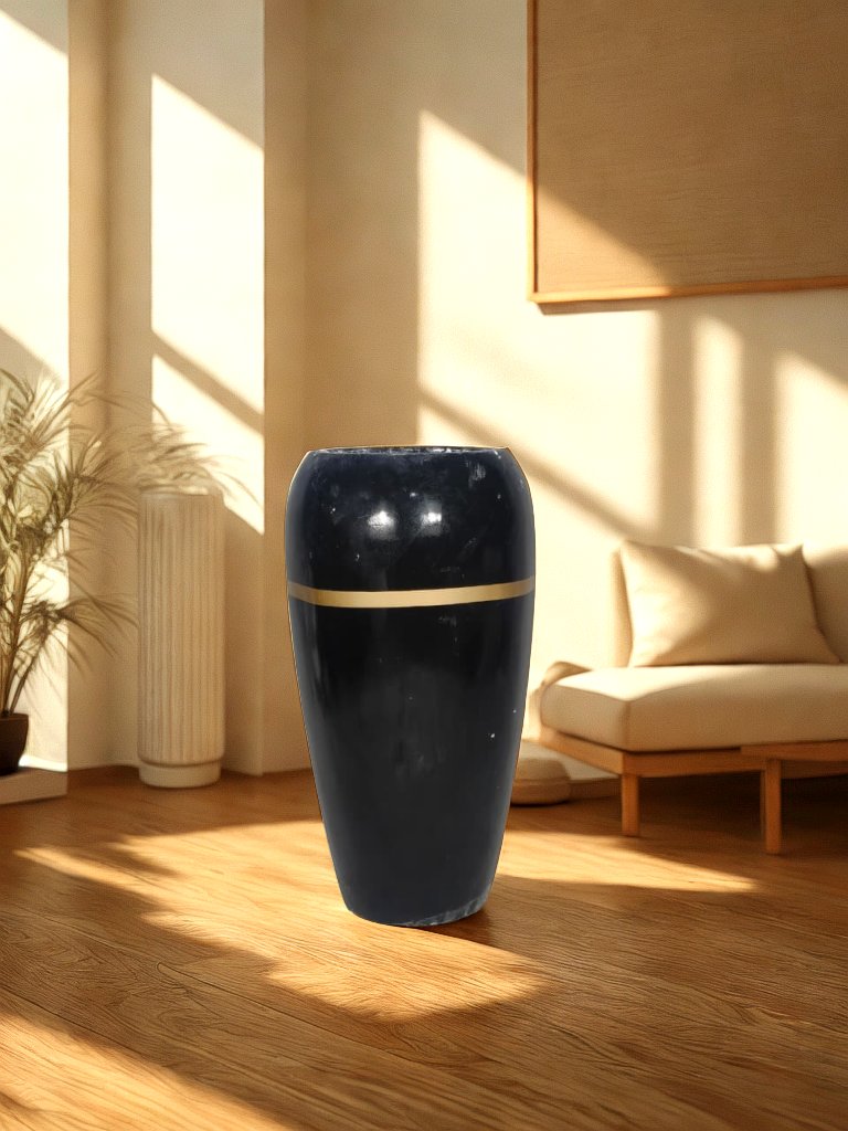 Tall glossy black fiberglass planter with a narrow gold-tone band styled in a warm living room.