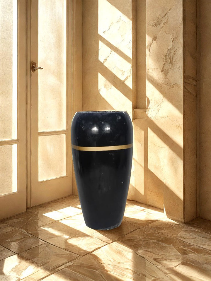 Tall glossy black fiberglass planter with a narrow gold-tone band displayed in a neutral entryway.