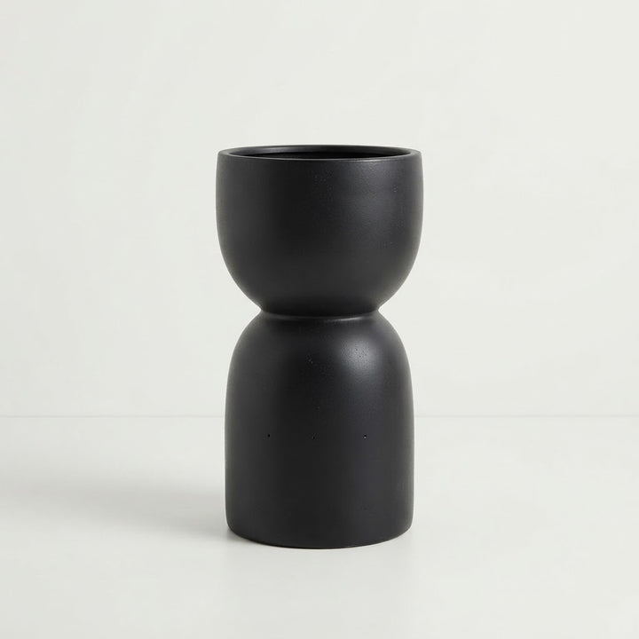 Glossy black fiberglass planter with a rounded bowl and tall sculptural pedestal-style base on a plain white studio background.