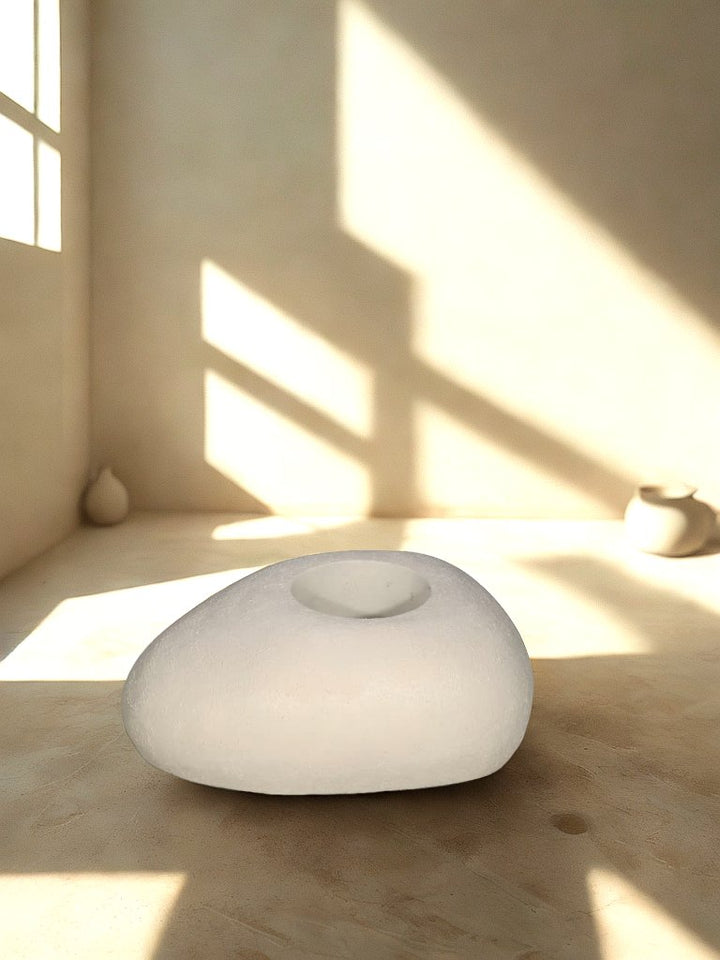 Cream pebble-shaped textured fiberglass planter with a recessed round opening in a softly lit neutral interior.