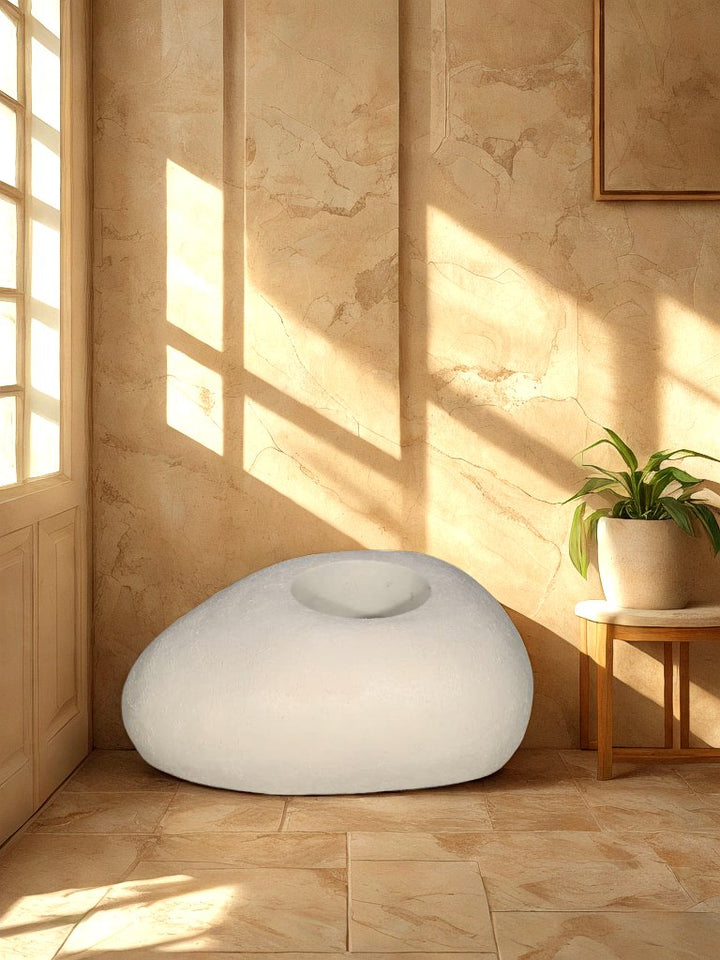 Cream pebble-shaped textured fiberglass planter with a recessed round opening displayed in a neutral entryway.