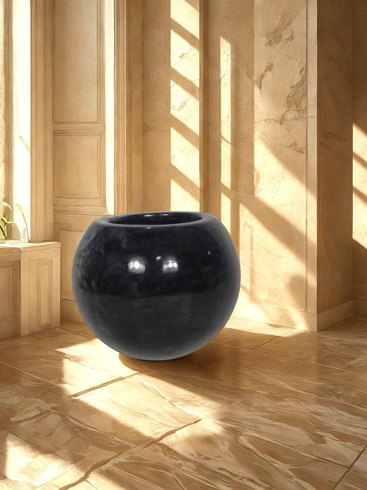 Glossy black round fiberglass planter with a wide circular opening displayed in a neutral entryway.