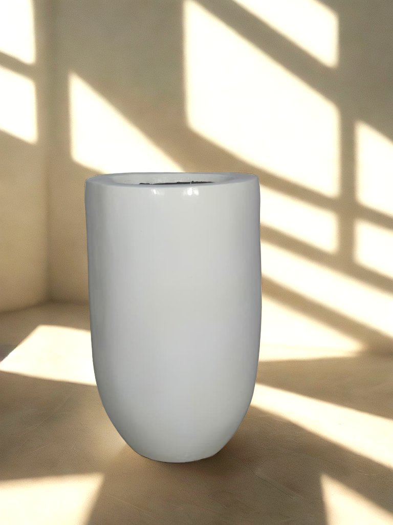 Tall glossy white fiberglass planter with a rounded base in a softly lit neutral interior.