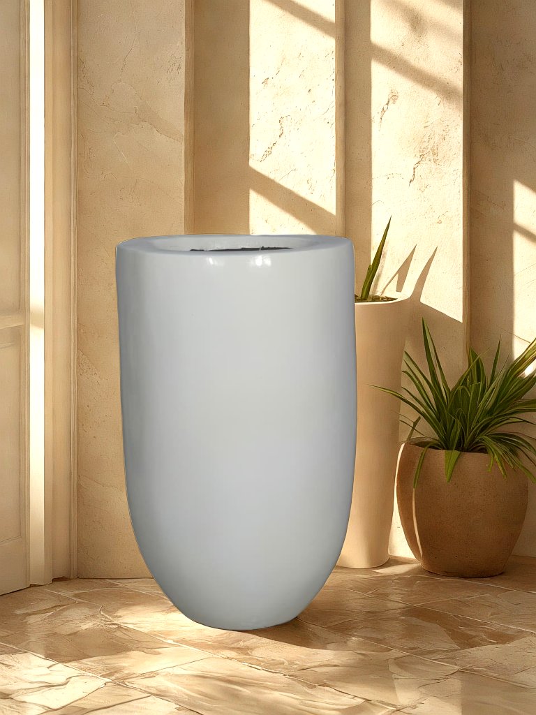 Tall glossy white fiberglass planter with a rounded base displayed in a neutral entryway.