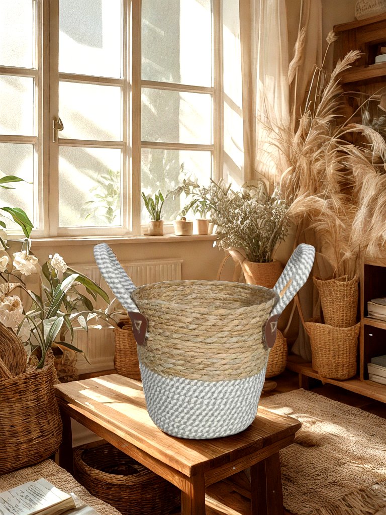 Natural and grey woven basket planter with two rope handles on a wooden stool in a sunlit room with decorative plants.