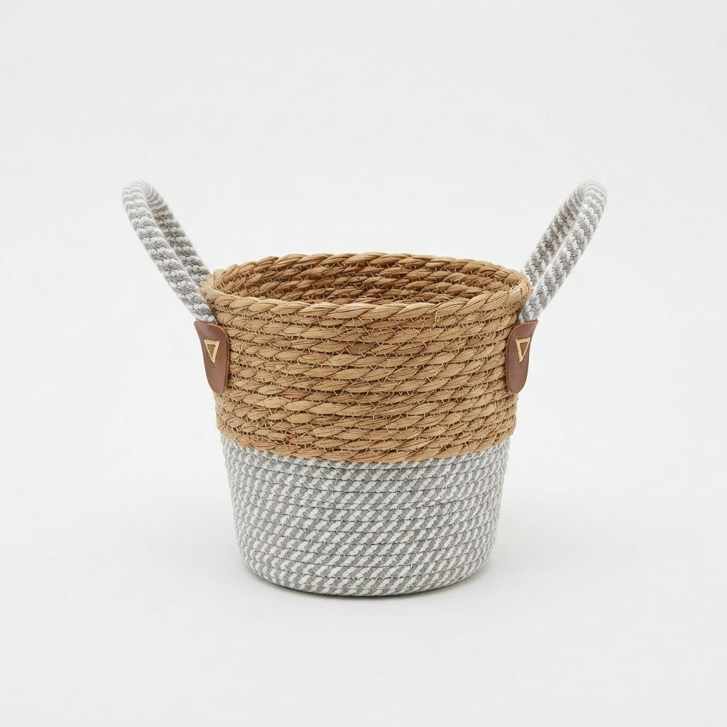 Natural woven basket planter with grey and white rope base and two loop handles on a plain white studio background.