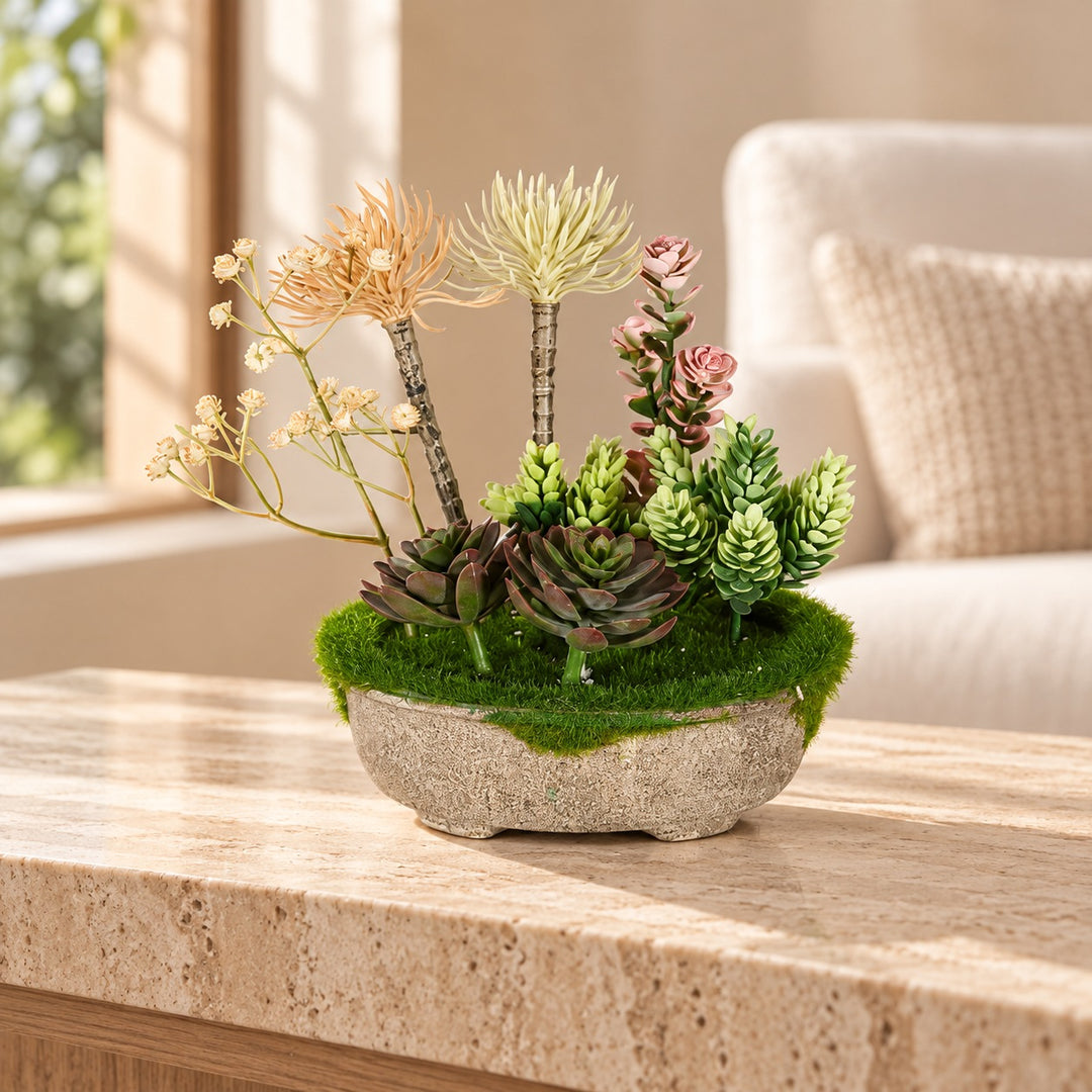 Mixed artificial succulents with blush and cream upright accents and moss in a rustic oval planter styled on a travertine table in an elegant neutral living room