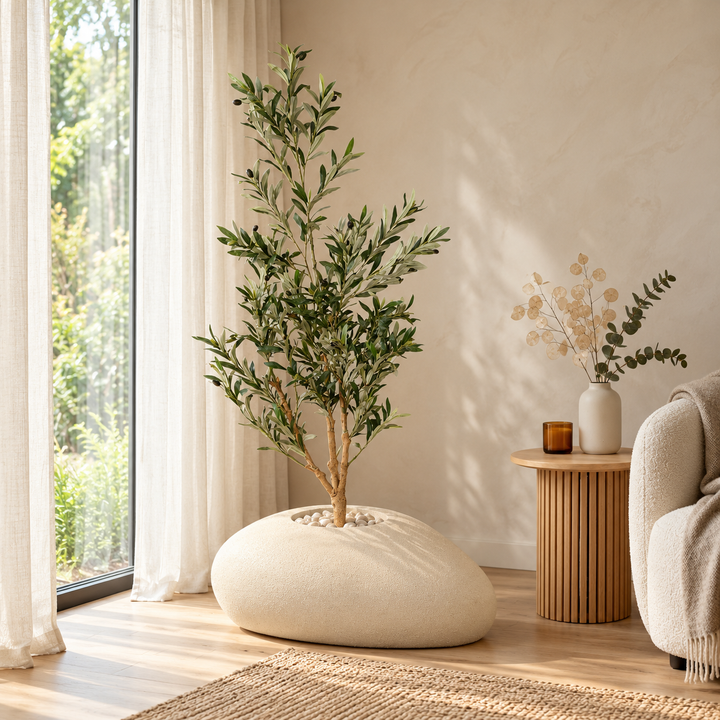 150 cm artificial olive tree with silvery green leaves and black olives in a wide low beige pebble-shaped fiberglass pot, styled with pale stones.