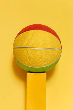 Wadi Home abstract geometric basketball art in yellow, red, and green, displayed on a yellow pedestal.
