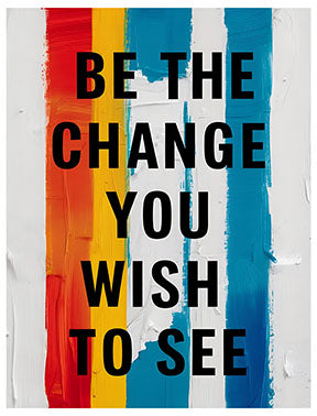 Wadi Home motivational wall art with black text "Be The Change You Wish To See" on a background of vertical red, orange, yellow, blue, and white brushstrokes.