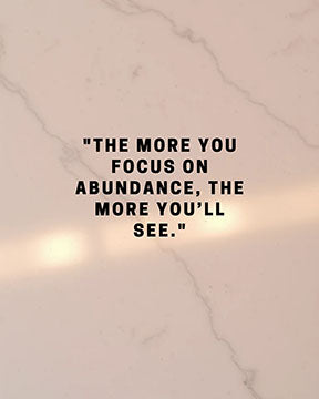 Wadi Home inspirational wall art with "The more you focus on abundance, the more you'll see." quote on marble background.