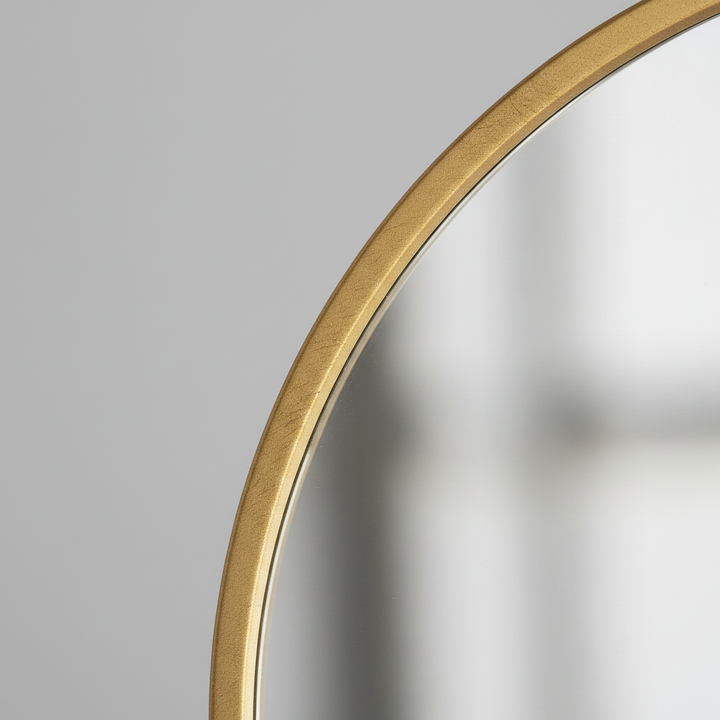 Close-up of the gold frame edge meeting the mirror glass
