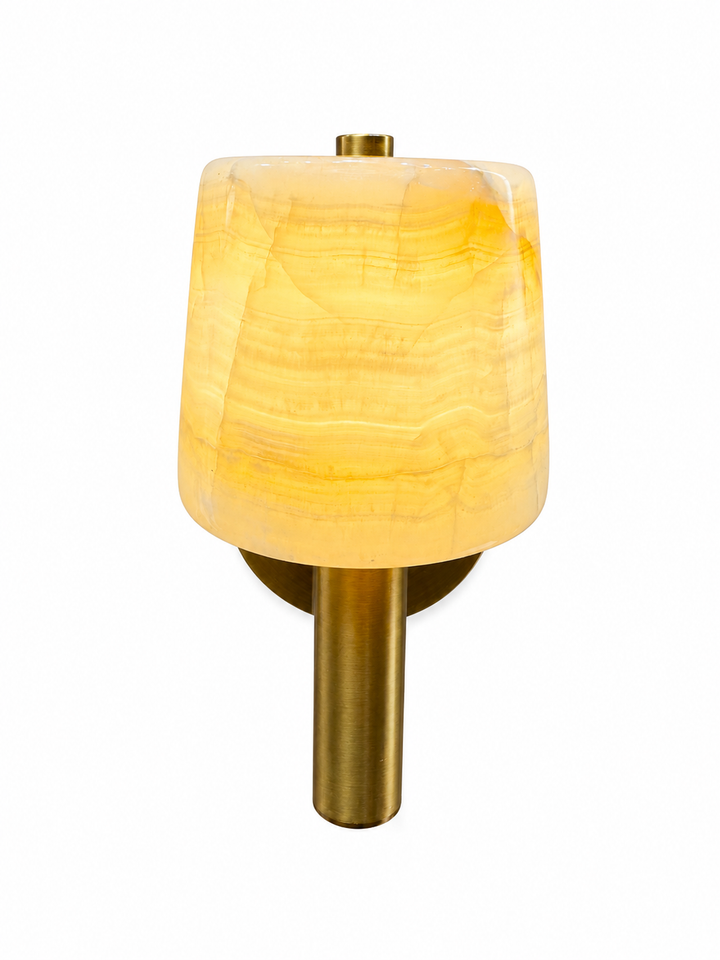 Luxury alabaster wall sconce featuring a natural stone shade and antique brass cylindrical stem, providing warm ambient lighting for modern interiors.