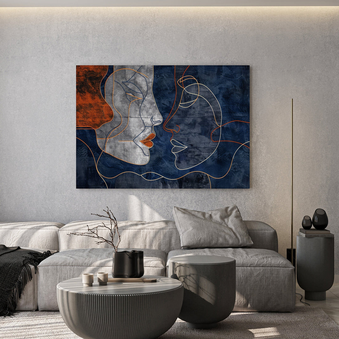 Wadi Home abstract faces line art canvas print with navy and terracotta tones hanging above a modern grey sofa.
