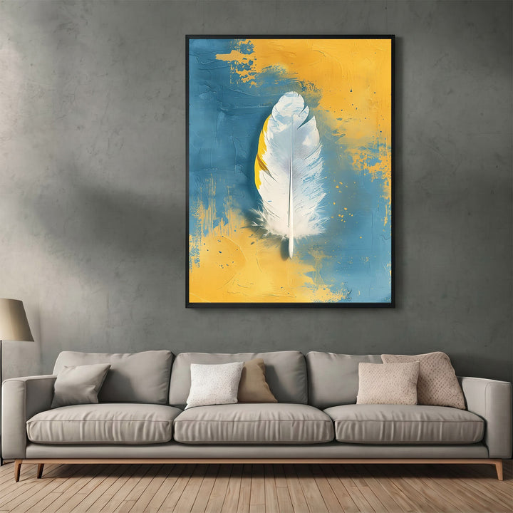 Wadi Home abstract feather canvas print with white feather on textured blue and yellow background above a grey sofa.