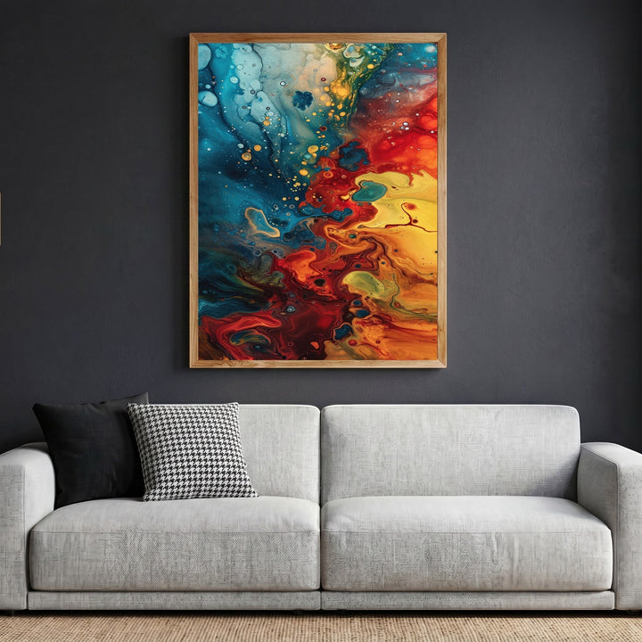 Wadi Home abstract fluid art canvas print with blue, red, and yellow swirls in a wooden frame above a grey sofa.