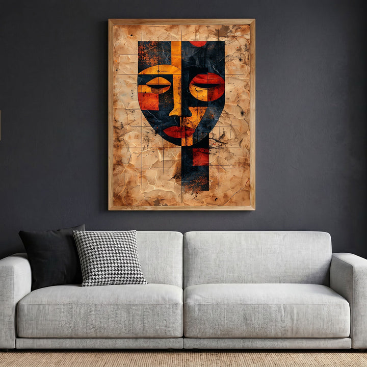 Wadi Home abstract geometric face wall art print with orange and black tones in a wooden frame above a modern sofa