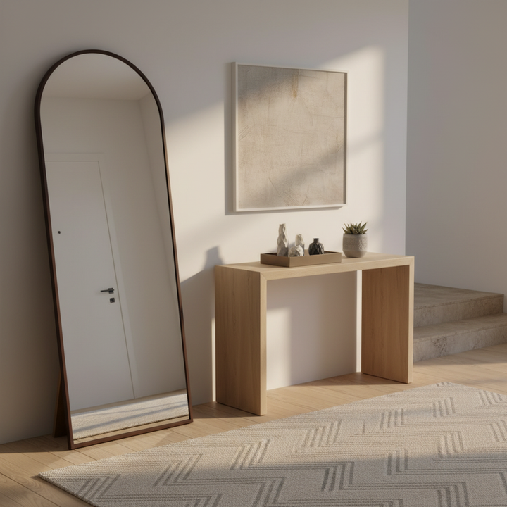 Wadi Home arched floor standing full length mirror with a dark wood frame leaning in a bright modern entryway.