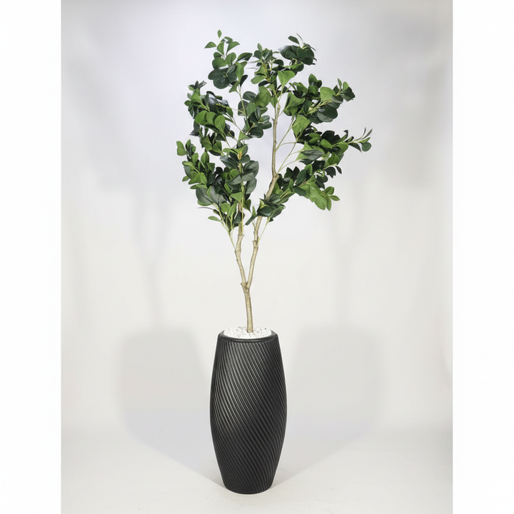 Wadi Home artificial Aralia tree with lush green leaves in a modern black spiral textured planter with white stones.
