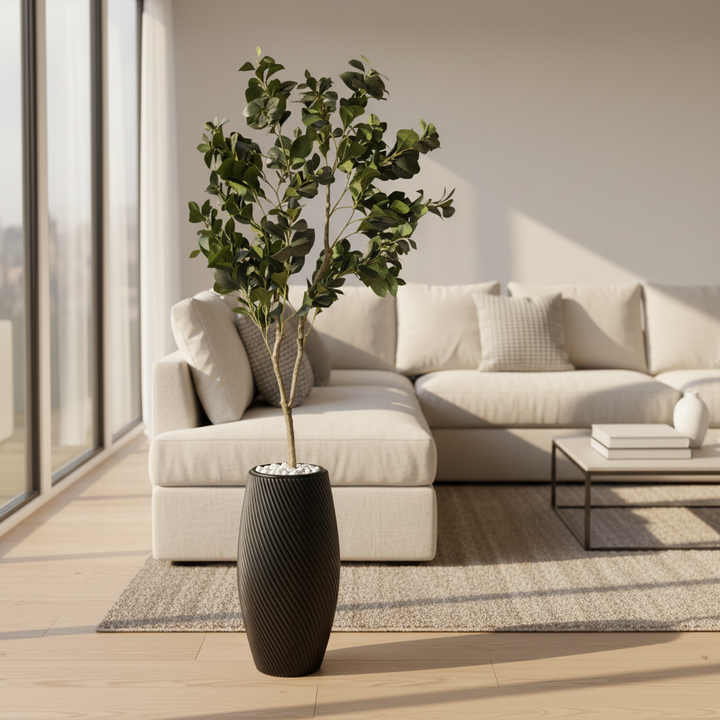 Wadi Home artificial Aralia tree with deep green leaves in a black textured spiral planter with white stone base.
